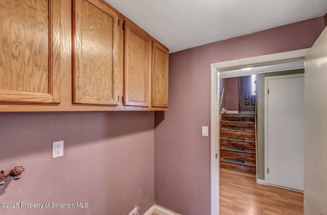 laundry area with light wood-style floors, baseboards, and cabinet space
