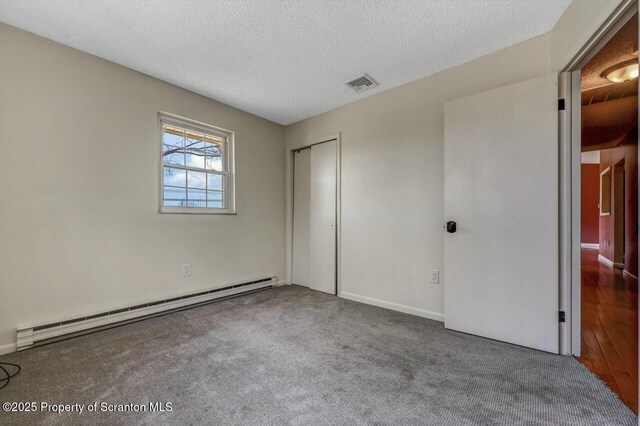 unfurnished bedroom featuring a baseboard radiator, carpet, a closet, visible vents, and a textured ceiling