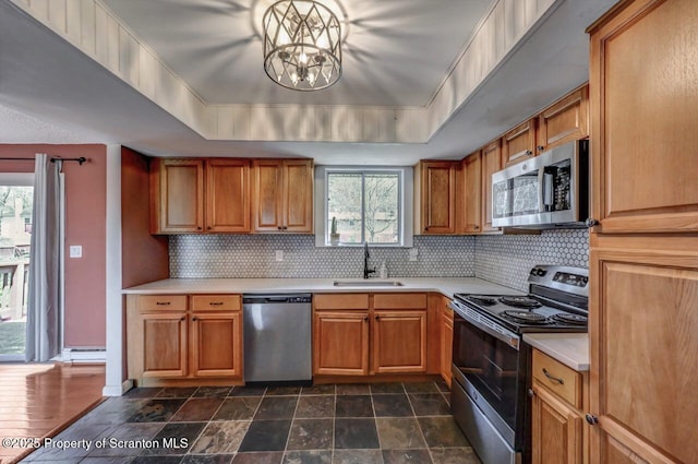 kitchen with stainless steel appliances, decorative backsplash, light countertops, and a sink