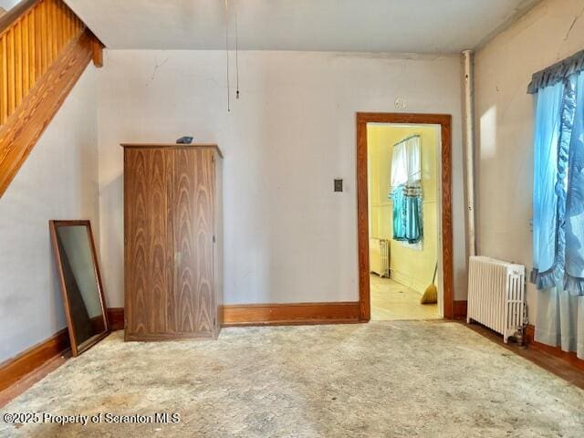 empty room with a healthy amount of sunlight, radiator, and light colored carpet