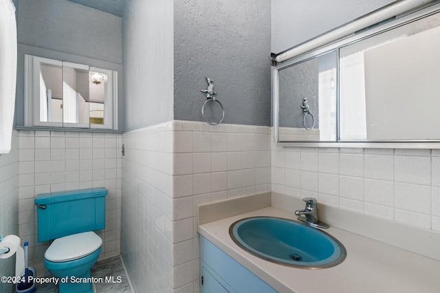 bathroom featuring vanity, toilet, and tile walls