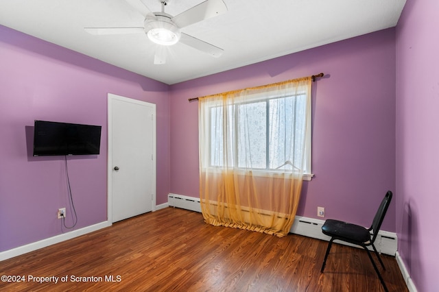 interior space with a baseboard heating unit, ceiling fan, and dark wood-type flooring