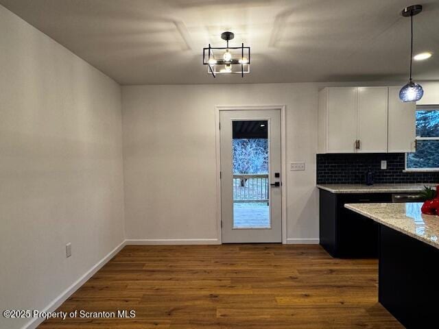 kitchen featuring light stone counters, dark hardwood / wood-style flooring, backsplash, decorative light fixtures, and white cabinets