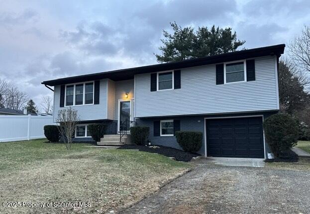 split foyer home with a garage and a front lawn