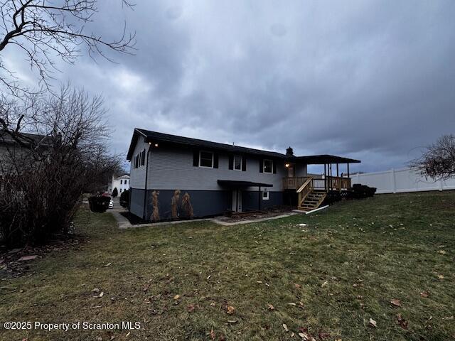 rear view of house with a lawn and a wooden deck