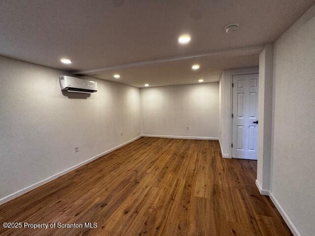 basement featuring an AC wall unit and wood-type flooring