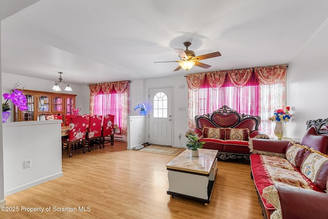 living room with light wood-type flooring and ceiling fan with notable chandelier