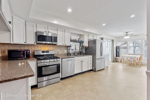 kitchen featuring dark stone countertops, decorative backsplash, sink, white cabinetry, and appliances with stainless steel finishes