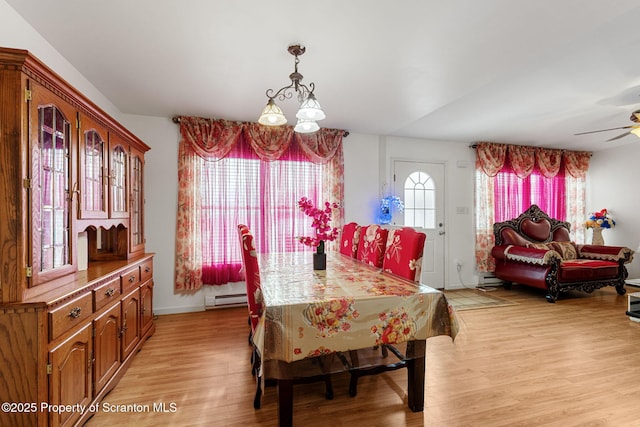 dining area with light wood-type flooring, baseboard heating, and ceiling fan with notable chandelier