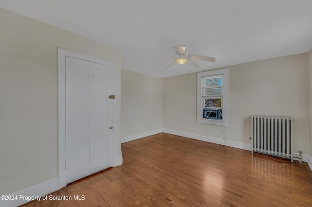 spare room featuring radiator heating unit, hardwood / wood-style flooring, and ceiling fan