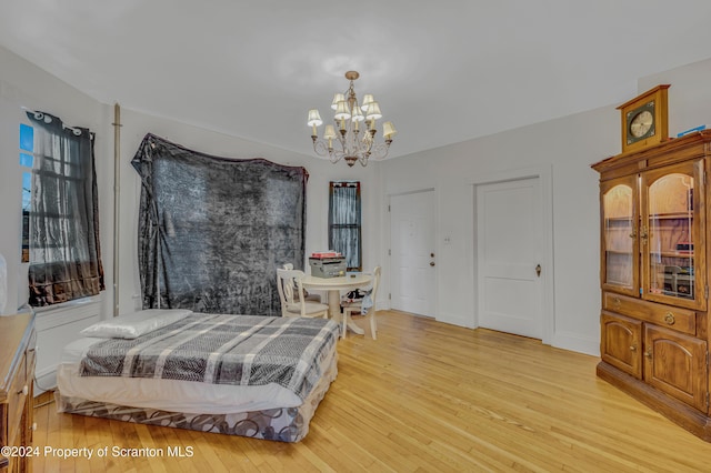 bedroom with light hardwood / wood-style floors and an inviting chandelier