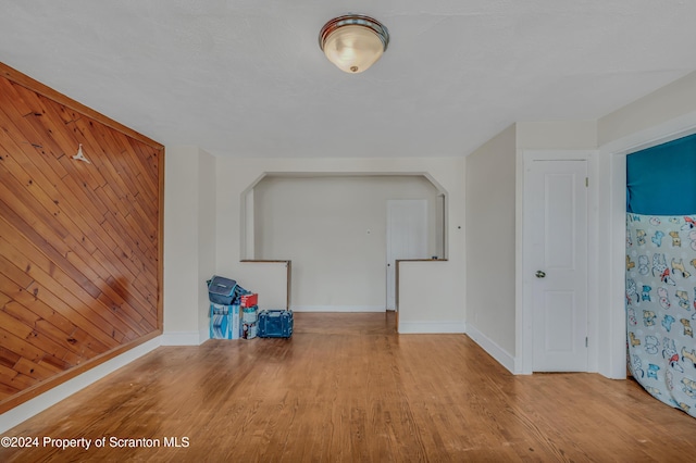 additional living space featuring light hardwood / wood-style floors and wood walls