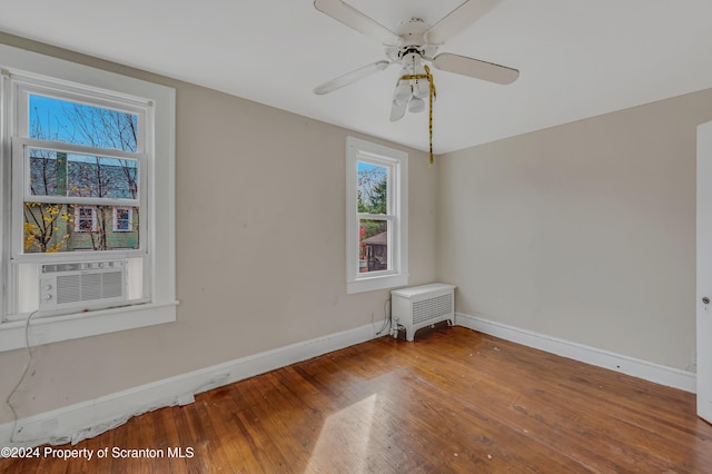 empty room featuring ceiling fan, cooling unit, and wood-type flooring