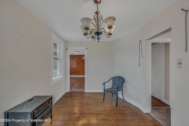 living area featuring wood walls, dark hardwood / wood-style flooring, and an inviting chandelier