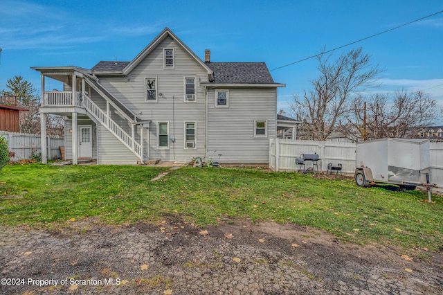 rear view of property featuring a balcony and a yard