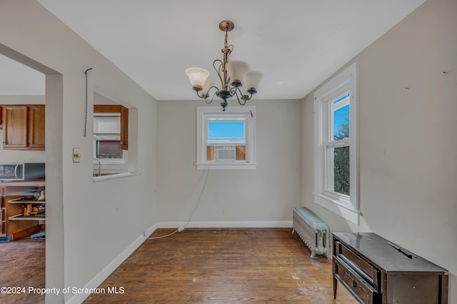 dining room with radiator, cooling unit, dark wood-type flooring, and a notable chandelier