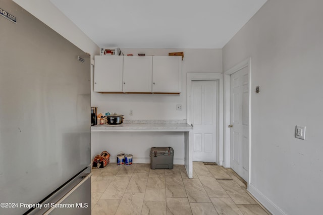 kitchen with stainless steel refrigerator and white cabinetry