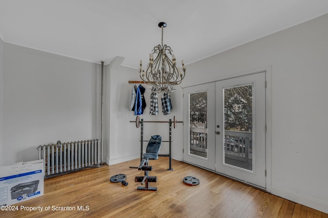 exercise room with hardwood / wood-style floors, an inviting chandelier, radiator, and french doors