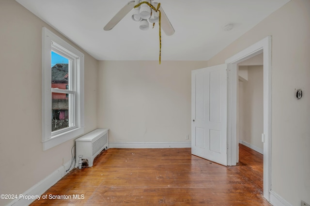 unfurnished room with ceiling fan, radiator heating unit, a wealth of natural light, and light hardwood / wood-style flooring