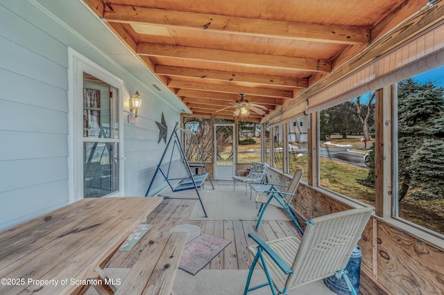 unfurnished sunroom featuring wood ceiling, a ceiling fan, and beamed ceiling