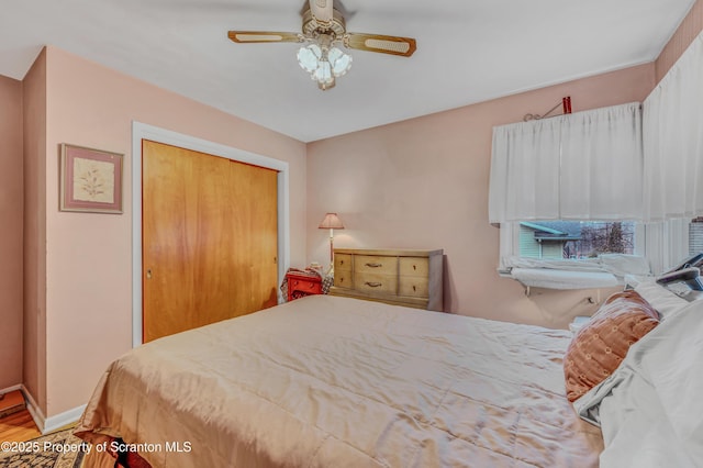 bedroom with a ceiling fan, baseboards, a closet, and wood finished floors