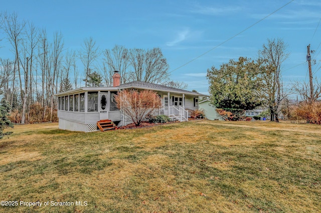 view of front of home featuring a sunroom, a chimney, and a front lawn