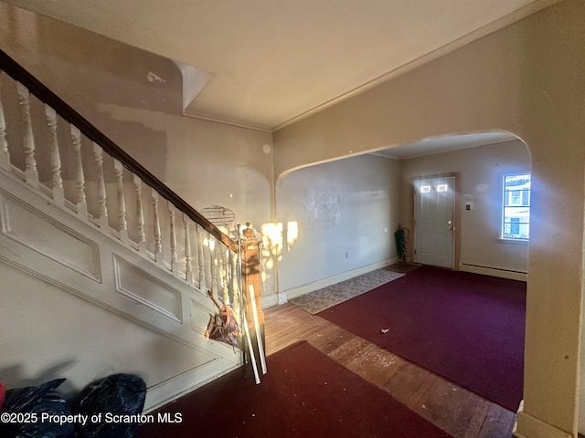 entryway with crown molding, a baseboard radiator, and wood-type flooring