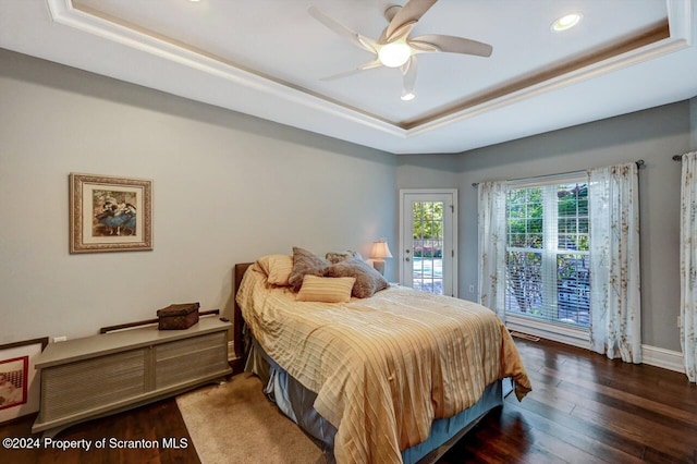 bedroom featuring ceiling fan, dark hardwood / wood-style flooring, a raised ceiling, and access to outside