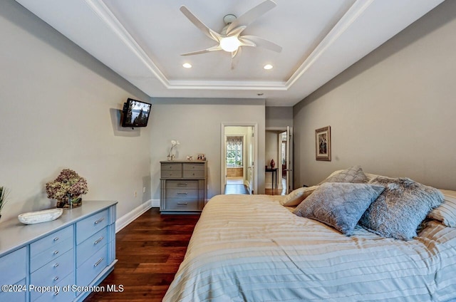 bedroom with a tray ceiling, ceiling fan, and dark wood-type flooring