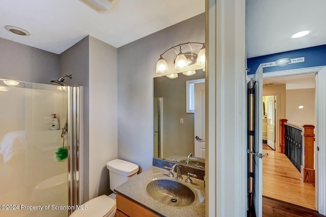 bathroom featuring a shower with door, vanity, hardwood / wood-style floors, and toilet