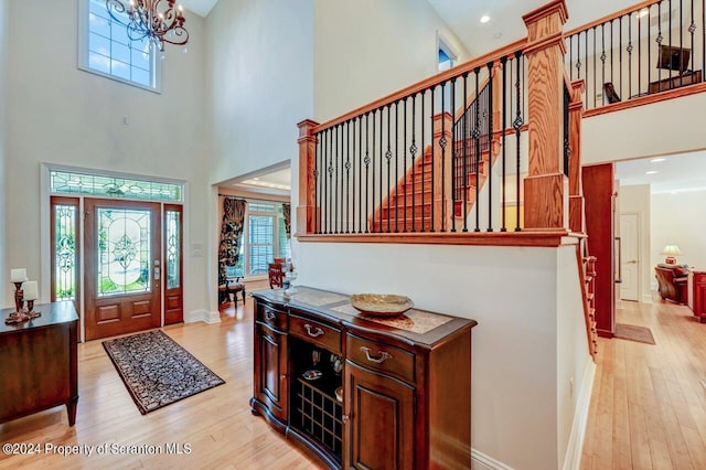 foyer entrance featuring a high ceiling, an inviting chandelier, and light hardwood / wood-style flooring