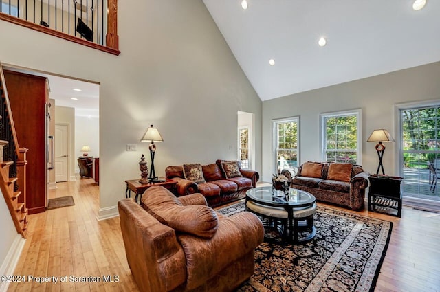 living room with light hardwood / wood-style floors and high vaulted ceiling