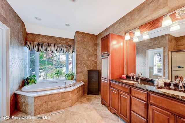 bathroom with tile patterned floors, vanity, separate shower and tub, and tile walls