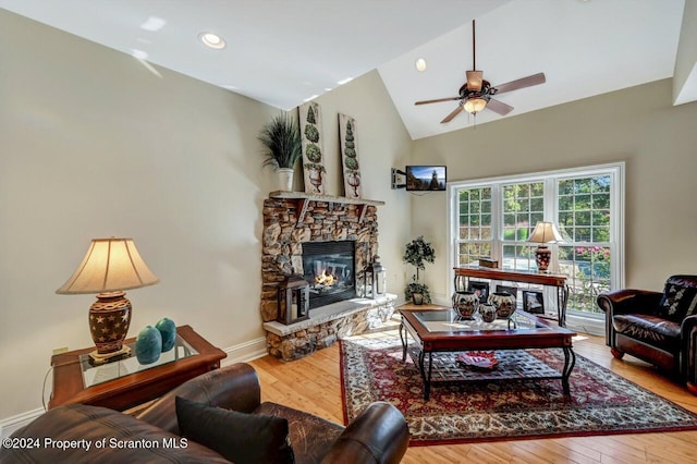 living room featuring hardwood / wood-style floors, ceiling fan, a fireplace, and vaulted ceiling