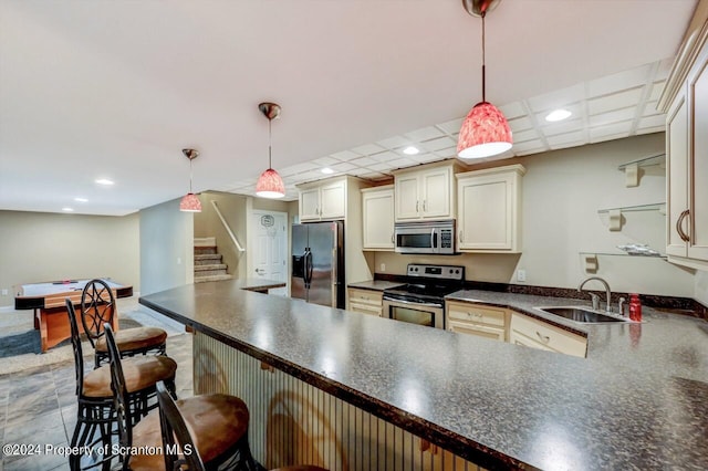 kitchen with kitchen peninsula, appliances with stainless steel finishes, decorative light fixtures, and sink