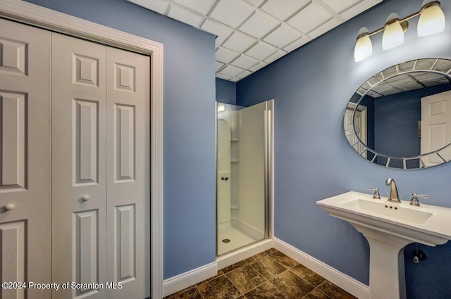 bathroom with a paneled ceiling and an enclosed shower