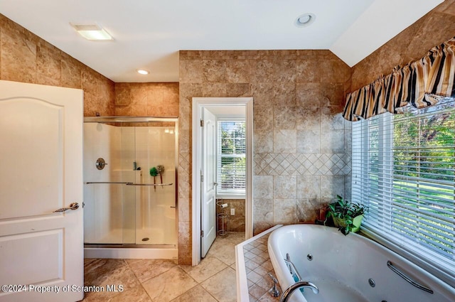 bathroom with vaulted ceiling, tile patterned flooring, independent shower and bath, and tile walls