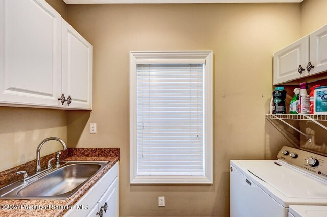 laundry area with washing machine and dryer, sink, and cabinets