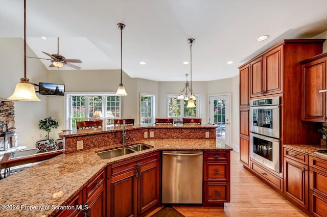 kitchen featuring light stone countertops, sink, stainless steel appliances, light hardwood / wood-style flooring, and ceiling fan with notable chandelier