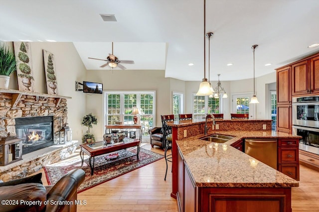 kitchen with decorative light fixtures, stainless steel appliances, sink, and an island with sink