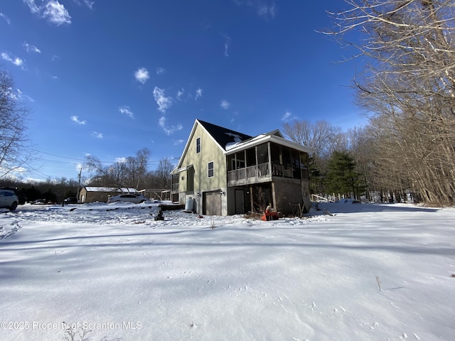 view of snowy exterior featuring a sunroom