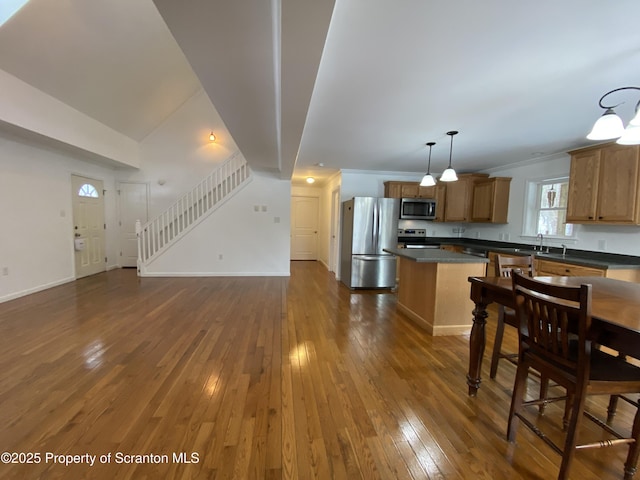 kitchen with pendant lighting, sink, dark wood-type flooring, stainless steel appliances, and a center island