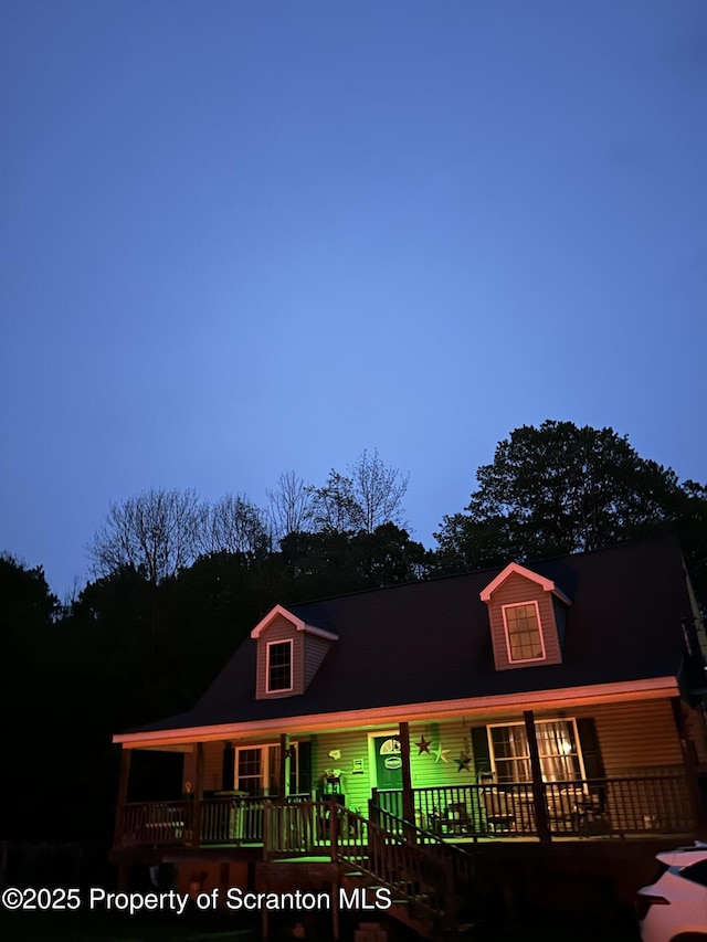 cape cod home featuring covered porch