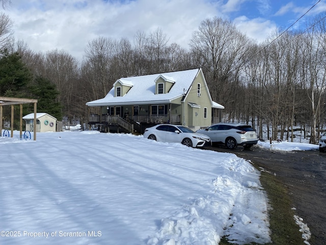 view of snowy exterior featuring a storage unit and covered porch