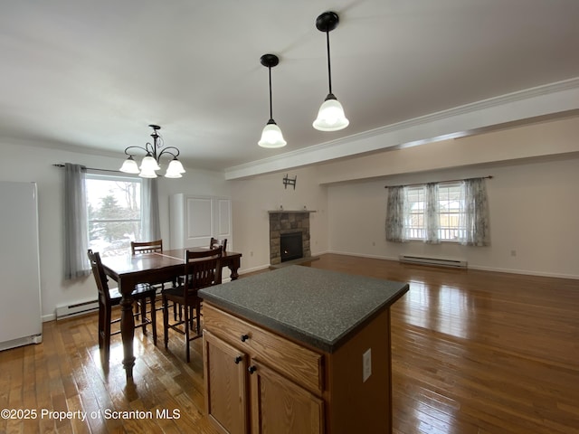 kitchen featuring dark wood-type flooring, a center island, ornamental molding, decorative light fixtures, and a baseboard radiator