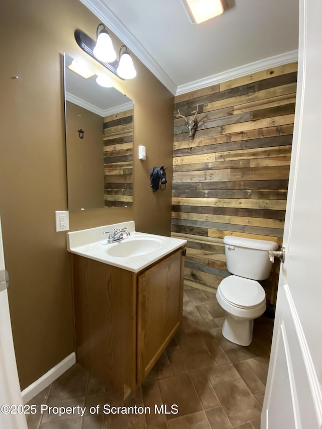 bathroom with tile patterned flooring, wooden walls, vanity, ornamental molding, and toilet