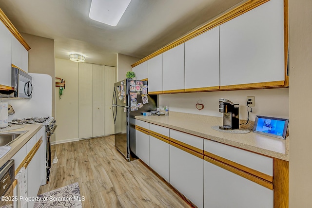 1504 Summit Pt Unit 1504, Scranton, PA 18508 - kitchen featuring white gas stove, white cabinets, light wood-style flooring, light countertops, and freestanding refrigerator