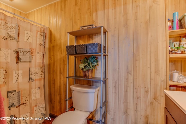 bathroom featuring toilet, wood walls, curtained shower, and vanity