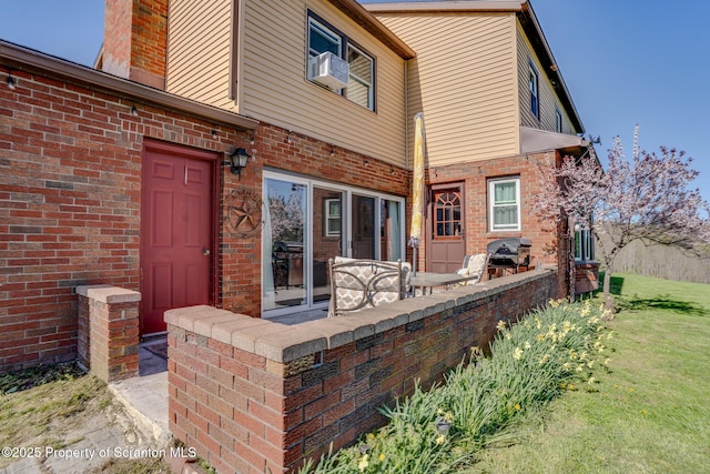back of house with brick siding, a lawn, and cooling unit