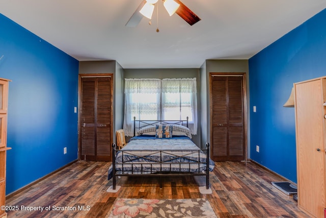 bedroom with baseboards, multiple closets, ceiling fan, and wood finished floors
